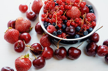 Strawberries, cherries, currant and blueberry on the white surface.
