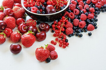 Strawberries, cherries, currant and blueberry on the white surface.
