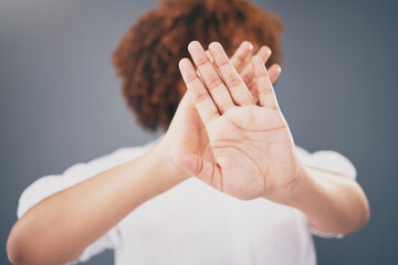 Closeup, hands and woman in studio for stop, warning or domestic violence symbol on grey background. Zoom, justice and hand of girl in protest, caution and protection, scared and abuse awareness