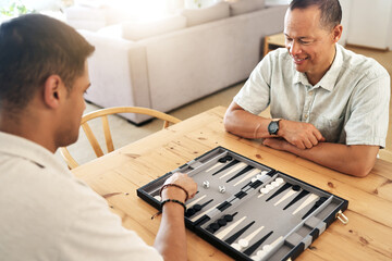 Senior, man and play backgammon in home with focus, strategy and contest for thinking, moving or son by table. Elderly man, board game competition and relax with bonding, love and family house lounge