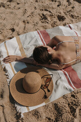 Beautiful woman chilling and sunbathing on the beach. Aesthetic stylish female sunglasses, straw...