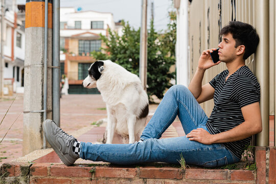 Focused man talking on smartphone near dog on stairs