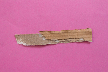 Torn cardboard piece on a pink background