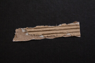 Ripped corrugated cardboard piece on a black background