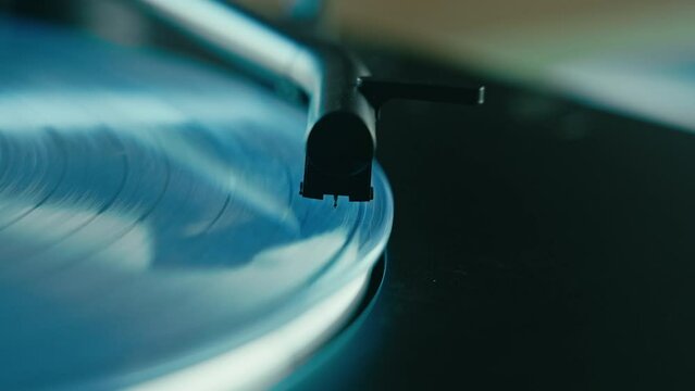 The vintage vinyl record player spins the colorful blue disc, while the turntable stylus plays music in the studio. It's a retro delight for any DJ set. Macro shot. 