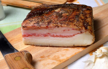 Piece of cured pork cheek on wooden cutting board.