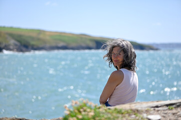 Portrait d'une femme cinquantenaire, cheveux aux vents, mer en arrière-plan 