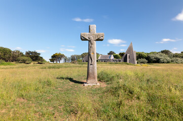 Grosse croix de granit, manoir en arrière-plan, herbe et ciel bleu