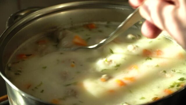 Boiling soup with meatballs close-up boils on the stove