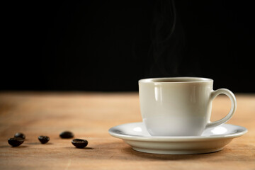 Coffee cup and coffee beans on wooden table. Black background.