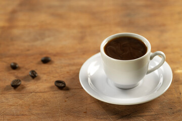 Coffee cup and coffee beans on wooden table. Black background.