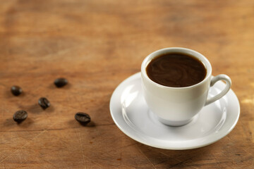 Coffee cup and coffee beans on wooden table. Black background.