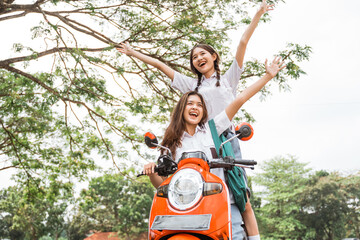 Fototapeta na wymiar Two high school girls riding motorbikes standing without helmets on the road