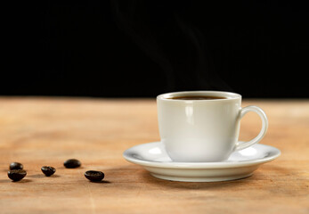 Coffee cup and coffee beans on wooden table. Black background.