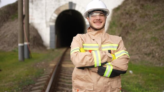 portrait of a positive and smiling railway engineer worker against the background of a tunnel looking into the camera