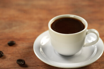 Coffee cup and coffee beans on wooden table. Black background.