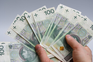 Wachlarz polskich banknotów 100 złotowych w dłoniach 