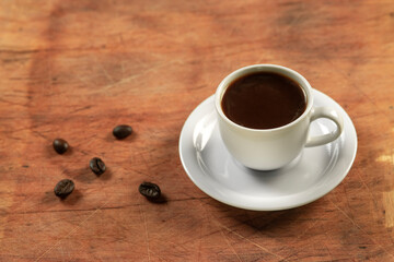 Coffee cup and coffee beans on wooden table. Black background.