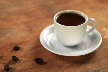 Coffee cup and coffee beans on wooden table. Black background.