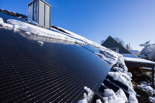 Mit Schnee bedeckte Solarpanele auf dem Dach eines Hauses in Deutschland