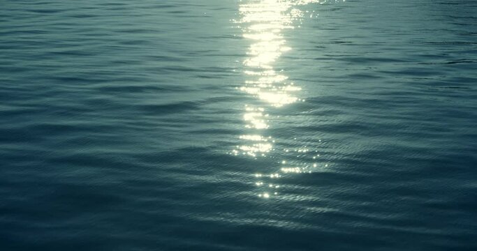Sunrise sunlight sparkles over ocean waves, slow motion