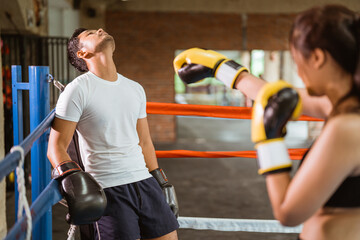 a male boxer pushed into the corner of the box ring while punched by the female boxer