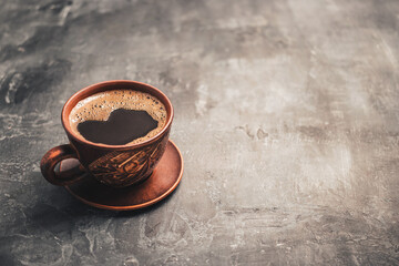 Black coffee drink in a brown clay cup on dark background with a copy space