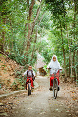 Obraz premium boy and girl in elementary school uniform cycling happily at country road