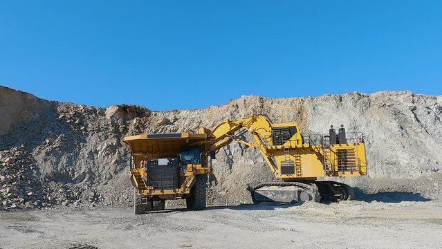 Industrial dumper trucks and wheel loader bulldozer working on open mine pit, slow motion