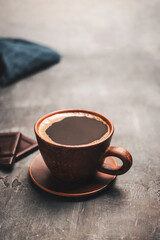 Black coffee drink in a clay cup and coffee beans in a spoon on dark background