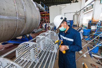 Male worker inspecting surface on heat exchanger, tube bundle industrial construction warehouse...