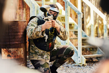 Fototapeta premium Paintball, target training or male soldier with gun in shooting game playing with on fun battlefield mission. Aim or focused man with army weapons gear for survival in outdoor challenge competition
