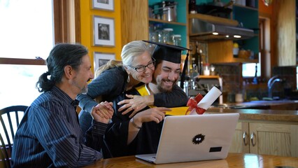Young man moves tassel to other site for virtual commencement ceremony for graduation, then smiles and everyone hugs.