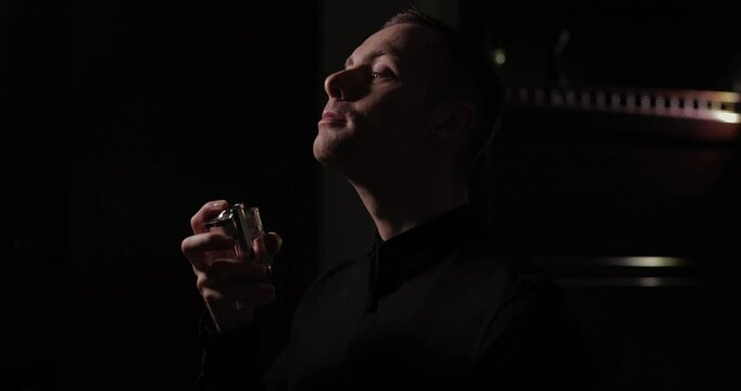 Man applying perfume on his neck, slow motion, black dark background