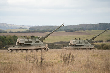 Fototapeta premium Two British army military AS90 (AS-90 Braveheart Gun Equipment 155mm L131) armoured self-propelled howitzers, guns pointing skywards, on a military exercise, Wilts UK