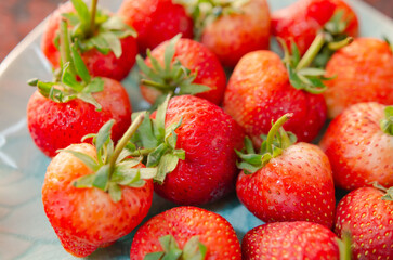 On the table are fresh strawberries in a beautiful dish.