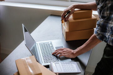 Small business entrepreneur, SME, freelance male working with boxes at home. Use a laptop for...