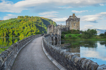 Stone bridge of Eilean Donan castle in early morning. Medieval Scottish castle reflecting in the water on a nice summer day. Castle in Scottish highlands. Cultural heritage of Scotland.