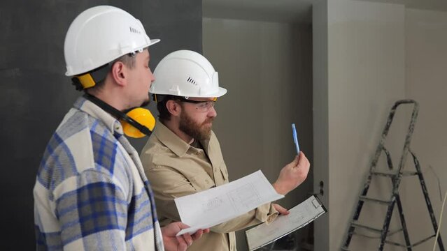 Side view, two engineers at a construction site using pens and a drawing explain the method of installing the device. Explanation of improvised objects at the construction site. High quality 4k