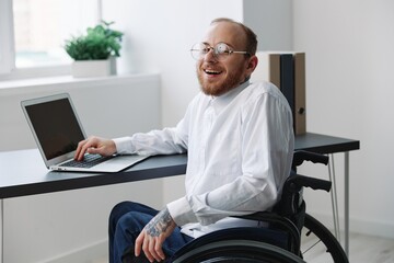 A man wheelchair, businessman in the office working laptop, working online, social networks startup, integration into society, the concept of working a person with disabilities, a real person close-up