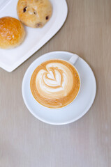A wooden table with a fragrant cappuccino and baked bread