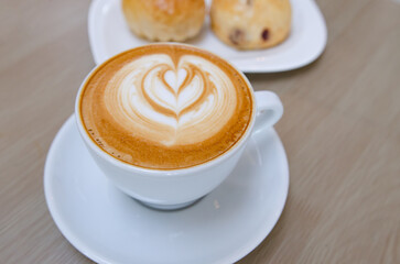 A wooden table with a fragrant cappuccino and baked bread