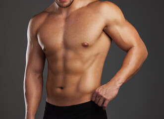 Shredded. Cropped shot of an unrecognizable and athletic young man posing shirtless in studio against a dark background.