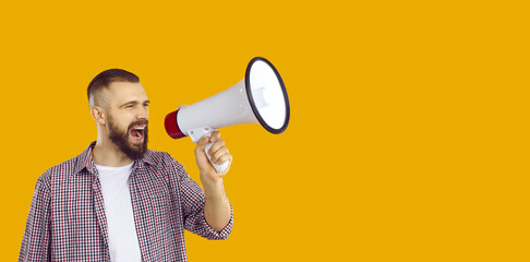 Shouting into megaphone. Young active man loudly announces crazy holiday discounts and sales using...