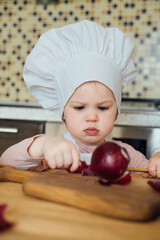 Little girl cooking in the kitchen wearing an apron and a Chef's hat.