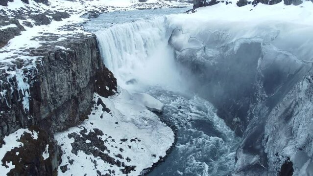 Dettifoss waterfall in Iceland, Frozen winter landscape with snow and ice aerial view 4k. Magical nature winter location with pure glacial water and huge current. Famous tourist attraction.