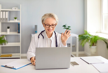 Professional doctor giving medical consultation. Happy woman in white coat with stethoscope sitting...