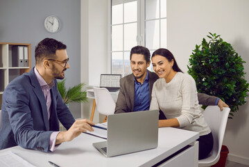 Young family couple meeting with professional real estate agent. Realtor sitting at his office...