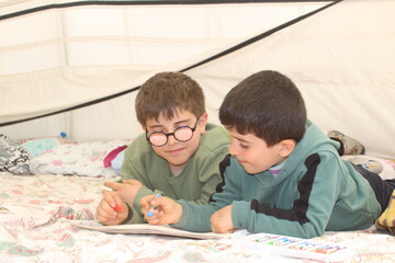 Earthquake survivor boys drawing in tent. 