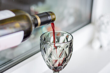 Red wine pouring from bottle. Wine glass with red wine. Alcohol drinks. Celebration background. Wine from bottleneck. Bar background. 
